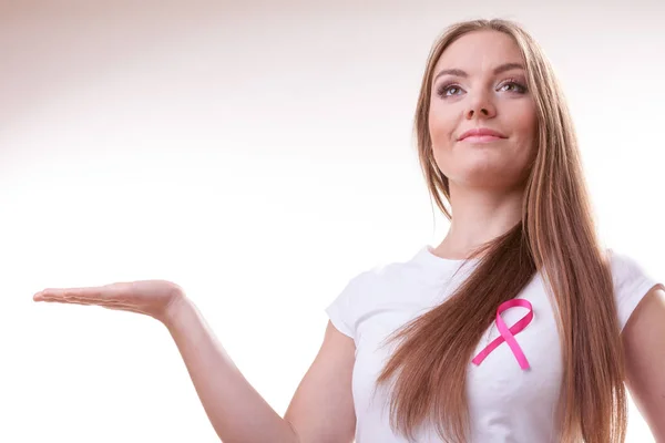 Женщина с розовой раковой лентой на груди держит руку открытой — стоковое фото