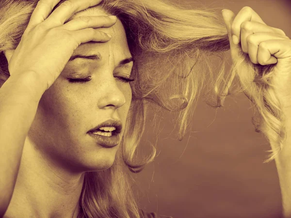 Sad woman looking at damaged hair ends — Stock Photo, Image