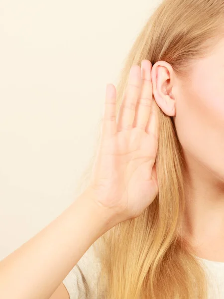 Mujer poniendo oreja de mano para oír mejor — Foto de Stock