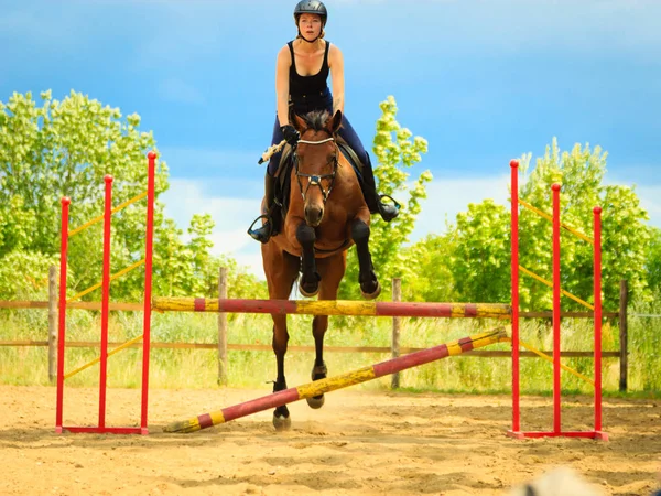 Jockey joven chica haciendo caballo saltar a través de obstáculo — Foto de Stock