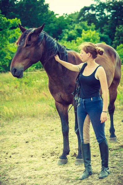 Jockey vrouw lopen met paard op weide — Stockfoto