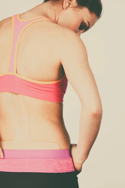 Kvinna med medicinsk kinesio taping på rygg — Stockfoto