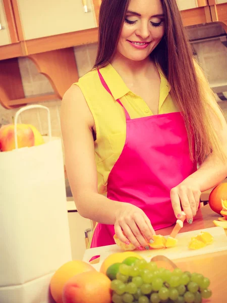 Žena v domácnosti v kuchyni řezání oranžové plody — Stock fotografie