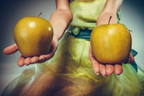 Mujer en vestido sosteniendo manzanas amarillas — Foto de Stock