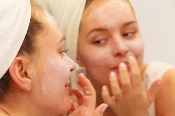 Mujer aplicando crema mascarilla en la cara en el baño —  Fotos de Stock