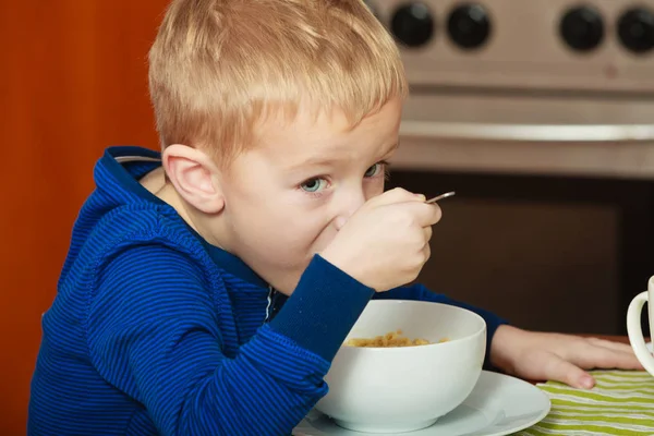 Kid boy eating breakfast, cereals and milk in bowl — Stock Photo, Image