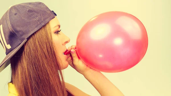 Female teenager inflating red balloon. — Stock Photo, Image
