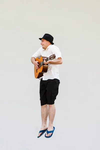 Man in zon hoed springen met gitaar — Stockfoto