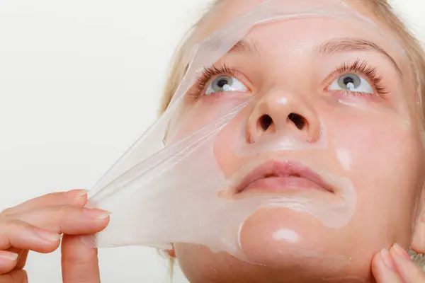 Kvinna att ta bort facial peel off mask. — Stockfoto