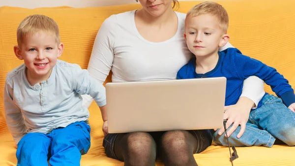 Dos niños pequeños y madre usando el ordenador portátil — Foto de Stock