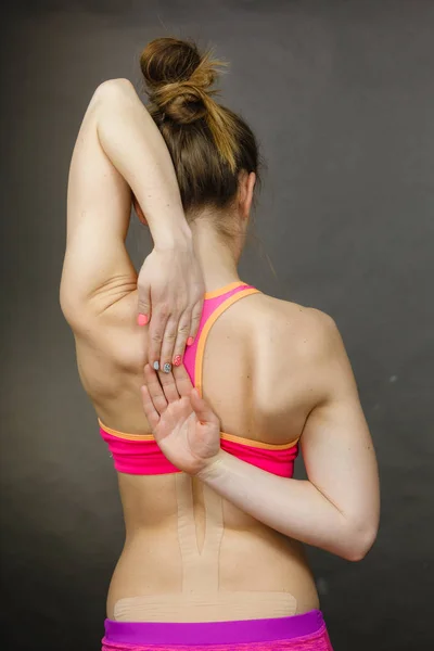 Sopiva nainen, jolla on lääketieteellinen kinesio nauha selässä — kuvapankkivalokuva