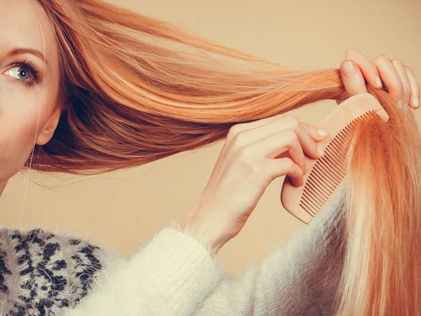 Девушка-блондинка расчесывает волосы расчёской — стоковое фото