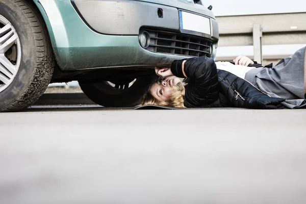 Mujer, reparando el coche roto que hay debajo. — Foto de Stock