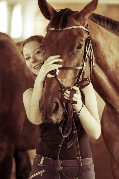 Vrouw knuffelen bruin paard in stal — Stockfoto