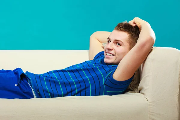 Ung man det lugnt på soffan på blå — Stockfoto