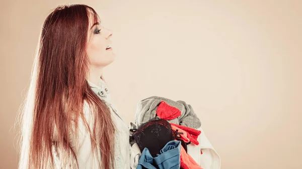 Vista lateral jovem mulher segurar pilha de roupas . — Fotografia de Stock