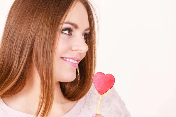 Flirty woman holding red wooden heart on stick — Stock Photo, Image