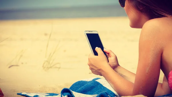Женщина на пляже пишет смс на смартфоне . — стоковое фото