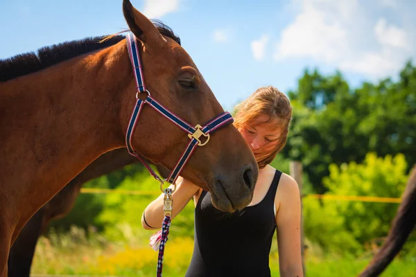 Jockey jong meisje aaien en knuffelen bruin paard — Stockfoto