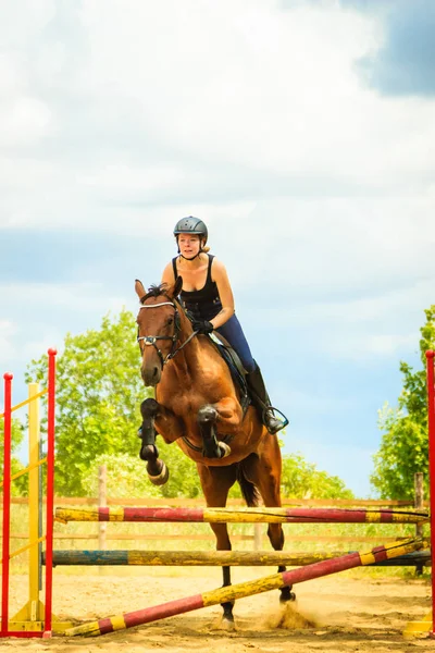 Jockey ung flicka gör hästen hoppa genom hindret Stockbild