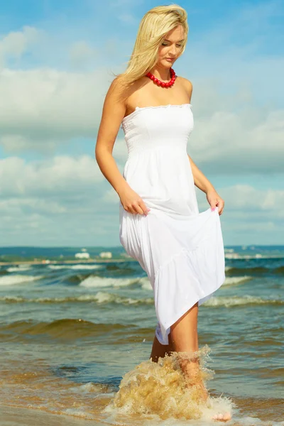 Blonde woman wearing dress walking in water — Stock Photo, Image