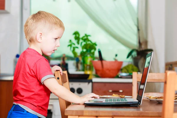 Маленький хлопчик з ноутбуком на столі вдома . — стокове фото