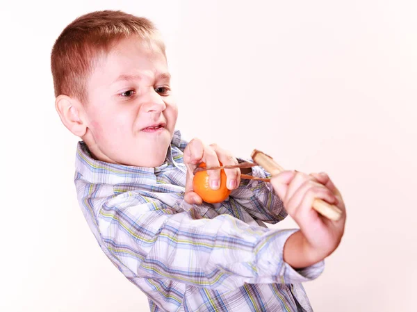 Jonge jongen gebruik sling shot schieten Mandarijn. — Stockfoto