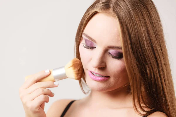 Woman applying loose powder with brush to her face — Stock Photo, Image