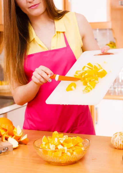 Mulher dona de casa na cozinha cortando frutas laranja — Fotografia de Stock