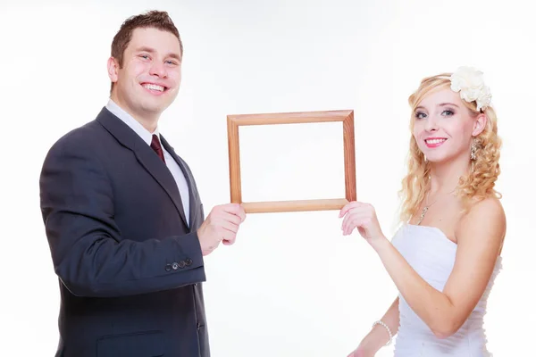 Groom and bride holding empty frame — Stock Photo, Image