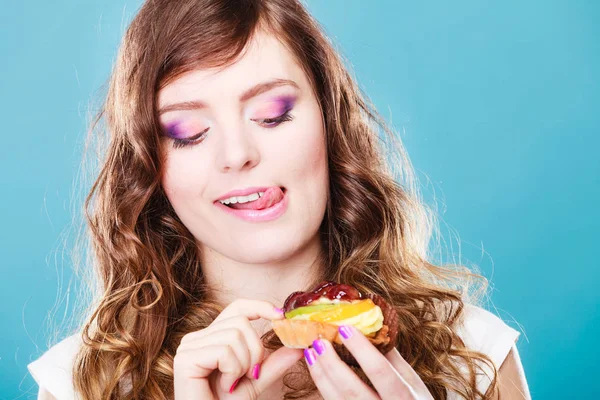 Cute girl holds fruit cake in hand on blue — Stock Photo, Image