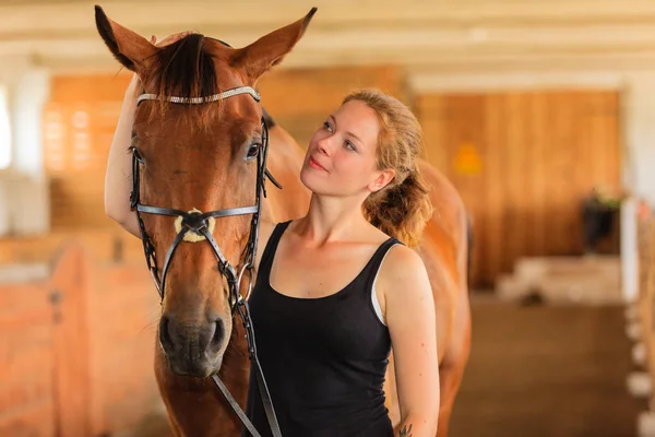 Jockey jong meisje aaien en knuffelen bruin paard — Stockfoto