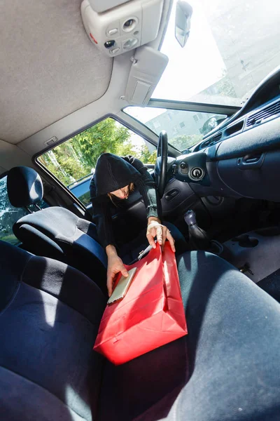 Zloděj zloděj krade smartphone a pytel od vozu — Stock fotografie