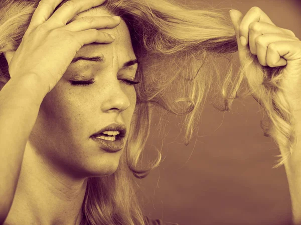Mujer triste mirando las puntas de cabello dañadas — Foto de Stock
