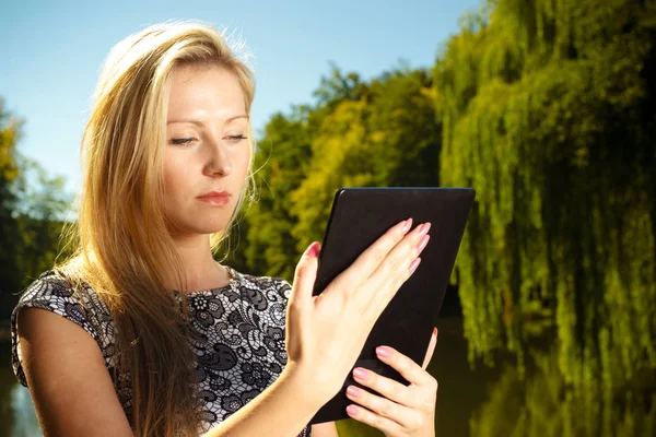 Žena sedí v parku, relaxační a používání tabletu — Stock fotografie