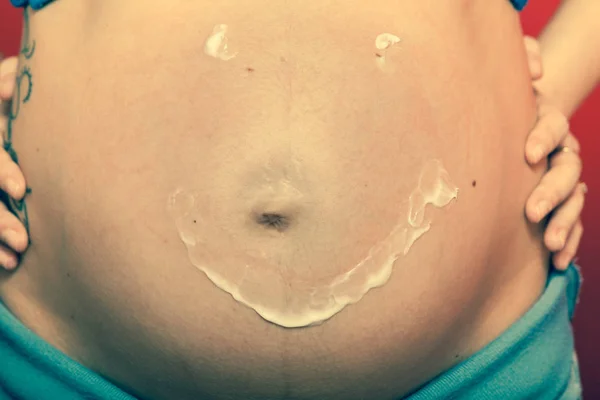 Pregnant woman having cream on big belly — Stock Photo, Image
