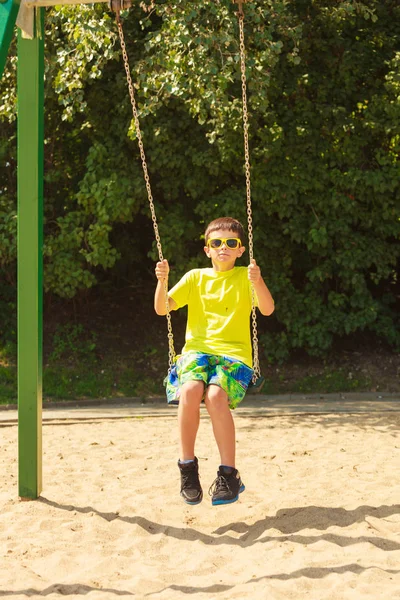 Ragazzo che gioca oscillando da swing-set. — Foto Stock