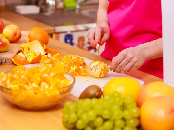 Donna casalinga in cucina taglio frutta arancione — Foto Stock