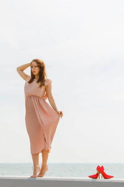 Kobieta nosi długie, jasne różowa sukienka na molo — Zdjęcie stockowe