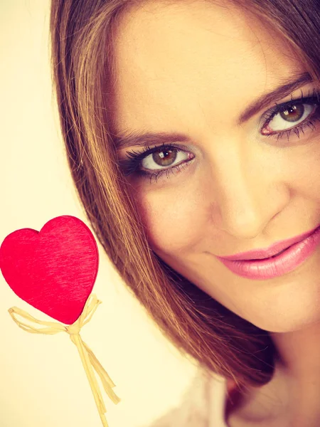 Mujer coqueta sosteniendo el corazón de madera roja en palo — Foto de Stock