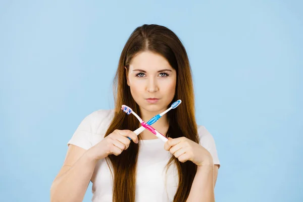 Женщина, держащая две зубные щетки, скрестила — стоковое фото