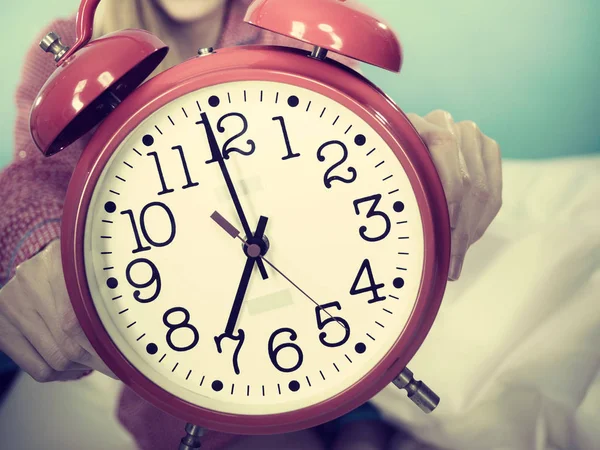 Mujer somnolienta usando pijamas sosteniendo reloj — Foto de Stock