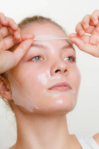 Frau entfernt Gesichtspeeling von Maske. — Stockfoto