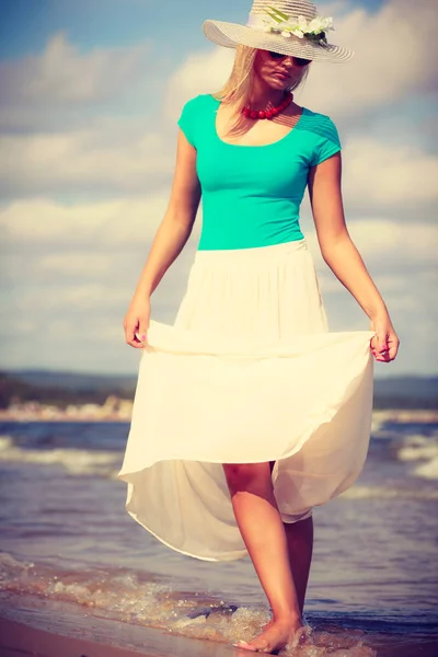 Blonde vrouw dragen jurk wandelen op strand — Stockfoto