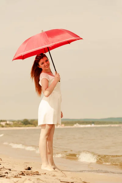 Redhead woman walking on beach holding umbrella — Stock Photo, Image