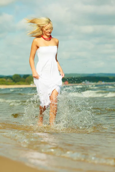 Mulher loira vestindo vestido andando na água — Fotografia de Stock