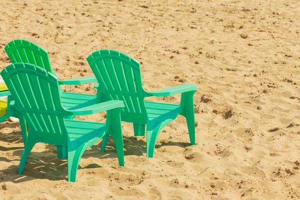 Green plastic chairs on sand. — Stock Photo, Image