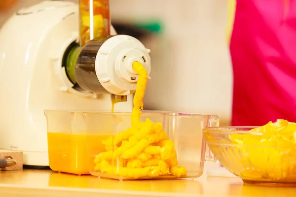Производство апельсинового сока в соковыжималке на кухне — стоковое фото