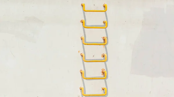 Yellow ladder on light grey conrecete wall — Stock Photo, Image