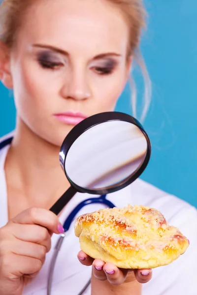Лікар зі збільшувальним склом, що вивчає солодку їжу — стокове фото
